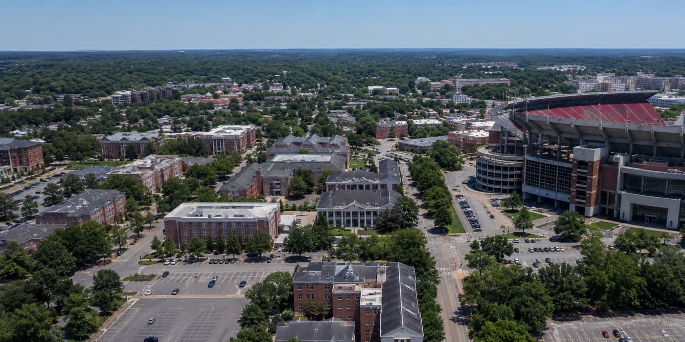 Aerial view of a university campus with brick buildings, tree-lined streets and a football stadium.